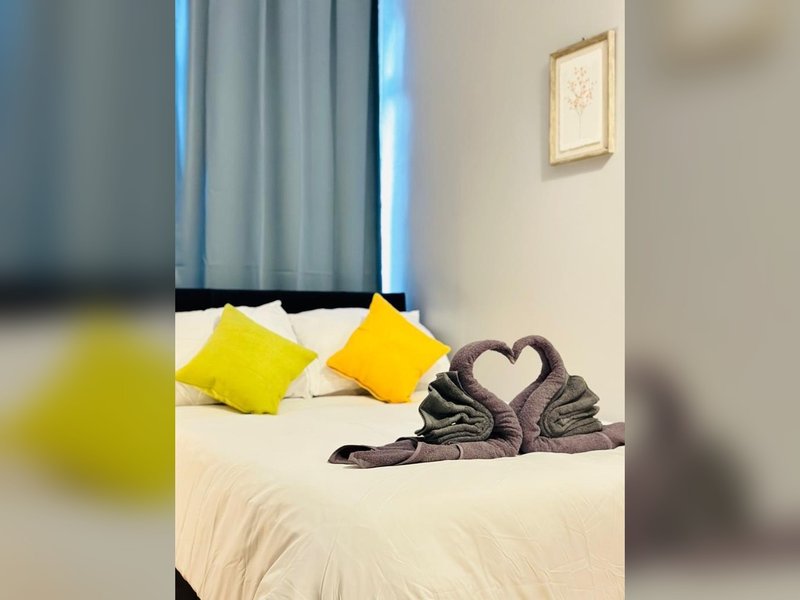 Bedroom with double bed, yellow cushions, decorative towel swans, and blue curtains