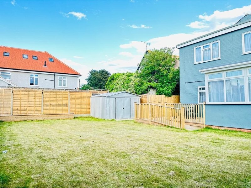 Rear garden with lawn, wooden fencing, storage shed and neighbouring properties