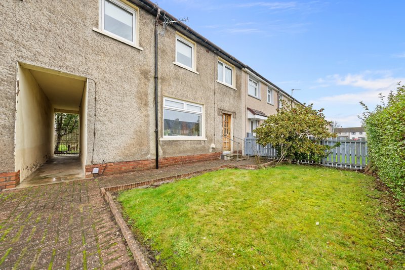Stone terraced house exterior with garden, driveway and green lawn