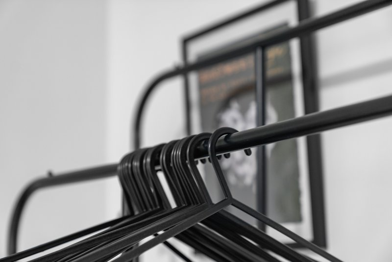 Black metal coat hangers on a rack near a window with white walls