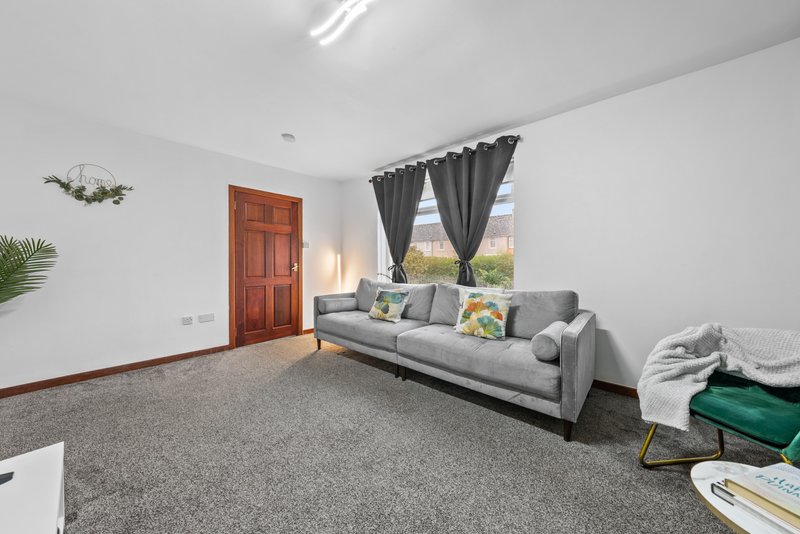 Spacious living room with gray sofa, black curtains, wooden door and potted plant