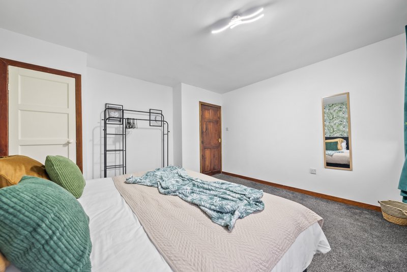 Spacious bedroom with double bed, bunk bed, green cushions and framed artwork on walls
