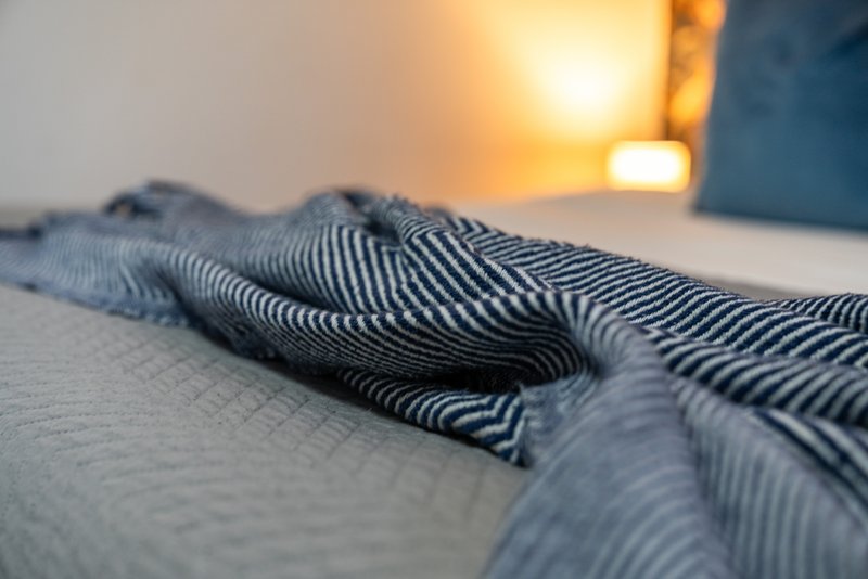 Rumpled striped bedding on bed with warm sunset lighting through window