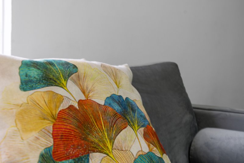 Decorative cushion with colorful floral pattern on gray upholstered sofa