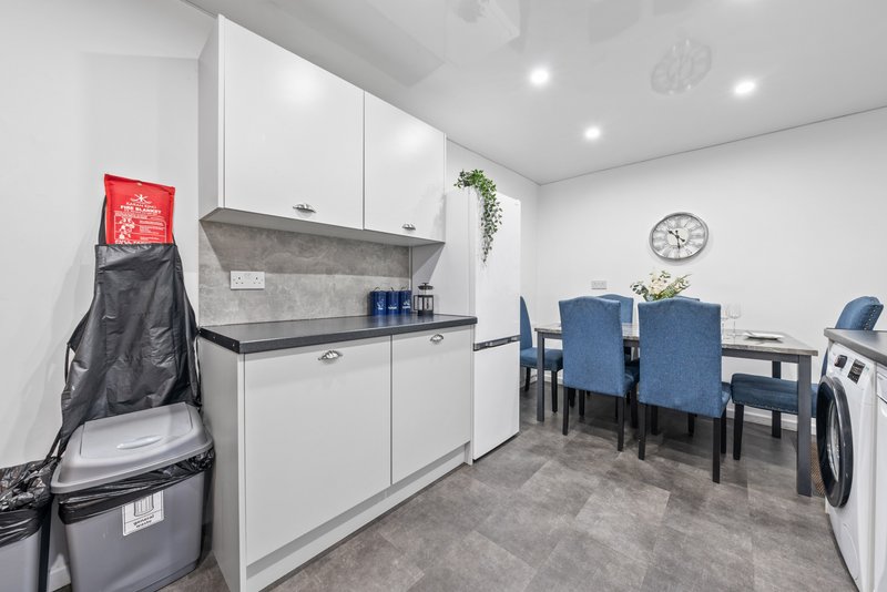 Modern kitchenette and dining area with white cabinetry, dining table, and appliances