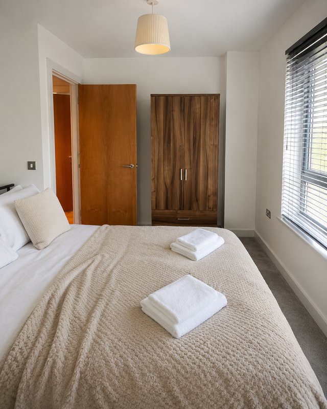 Bright bedroom with double bed, wooden wardrobe, cream bedding and pendant light fixture