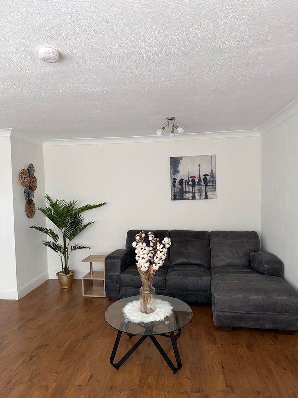 Modern living room with dark grey sectional sofa, round coffee table, potted plant and framed wall art