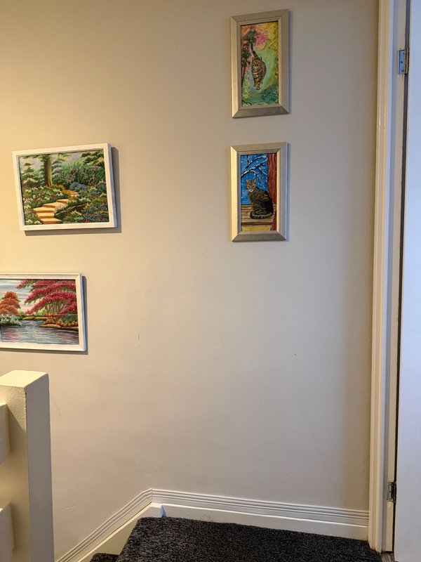 Hallway with framed landscape artwork on cream walls and dark entry mat