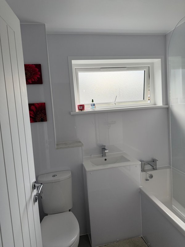 Modern bathroom with toilet, sink, bath, window, and red wall décor