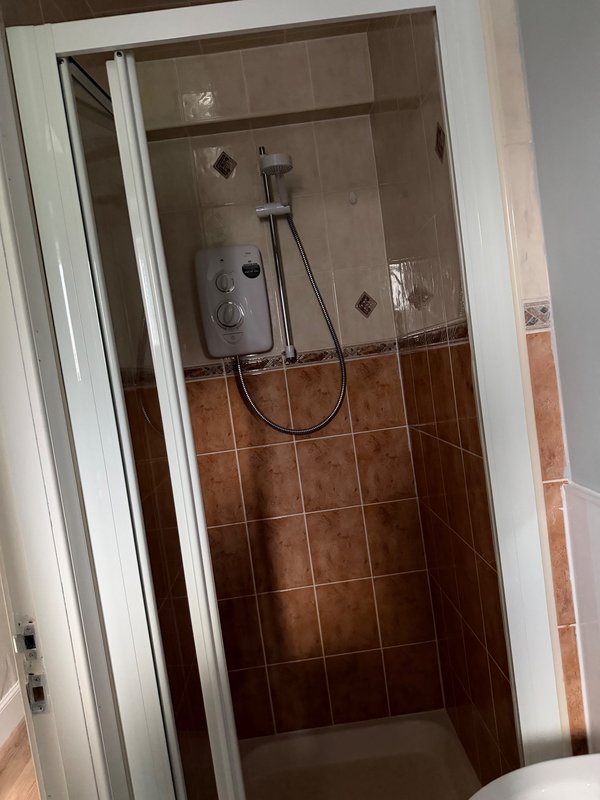 Bathroom shower enclosure with brown tile walls and modern showerhead fixture