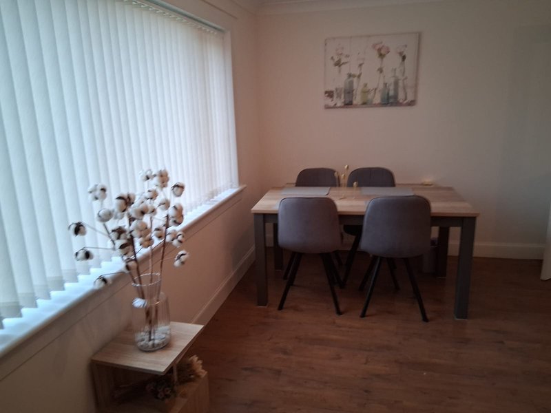 Dining room with wooden table, grey chairs, cotton stems in vase, and wall art