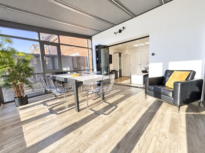 A bright and airy dining area with dining table (seats 8 when extended), relaxing black armchair and access to garden / patio.