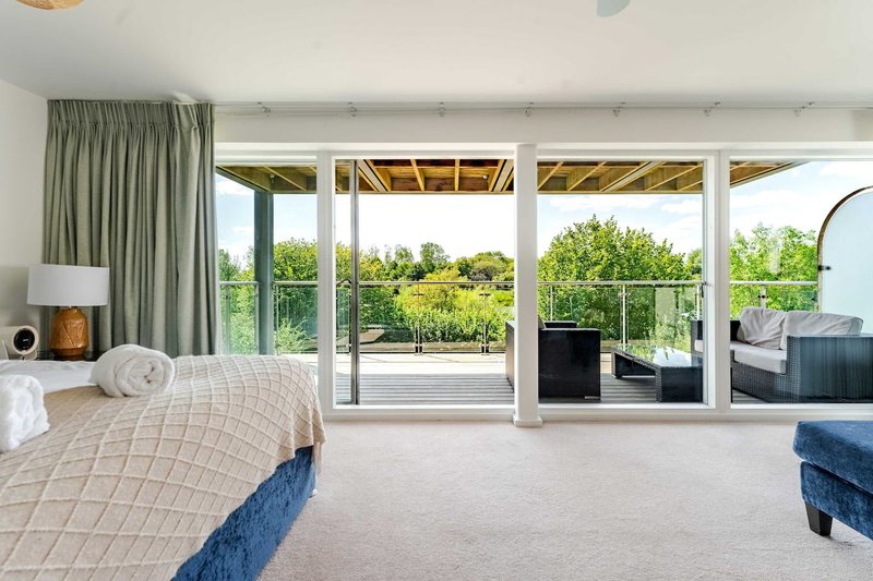 Spacious bedroom with double bed, large windows overlooking garden and deck area