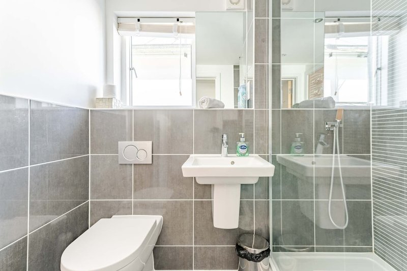 Modern bathroom with pedestal sink, toilet, enclosed shower and grey tile walls