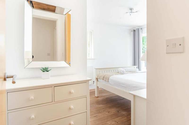 Modern bathroom with vanity, mirror, and wood drawers opening to bedroom beyond