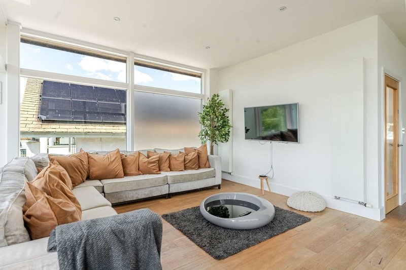 Modern living room with brown leather sofa, wooden floor, round coffee table and wall-mounted TV