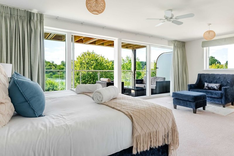 Spacious bedroom with double bed, blue cushions, seating area, and garden views through French doors