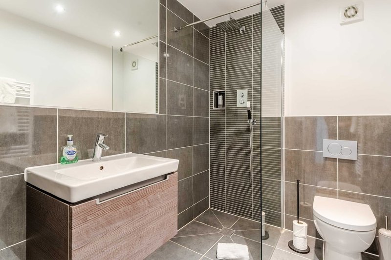 Modern bathroom with walk-in shower, vanity sink, toilet and tiled walls