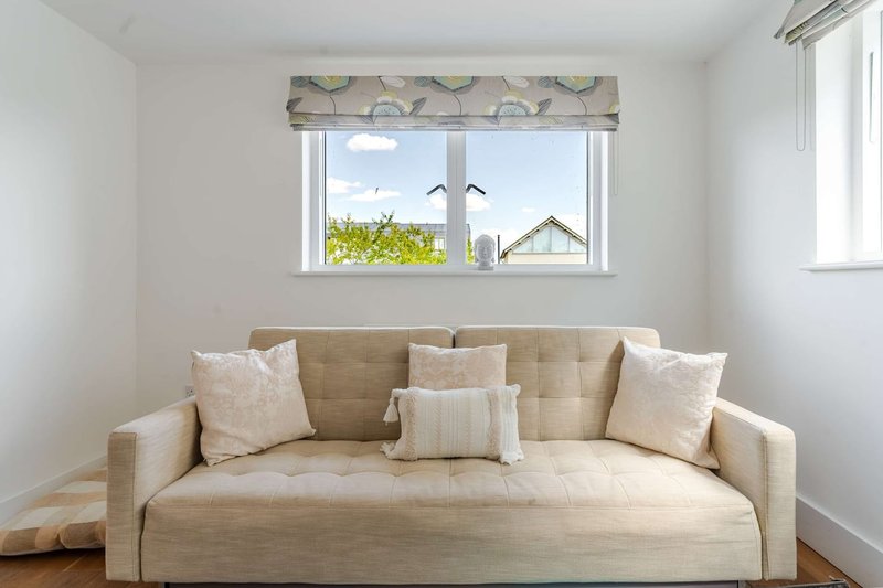 Bright living room with beige upholstered sofa, decorative pillows, and window with garden view