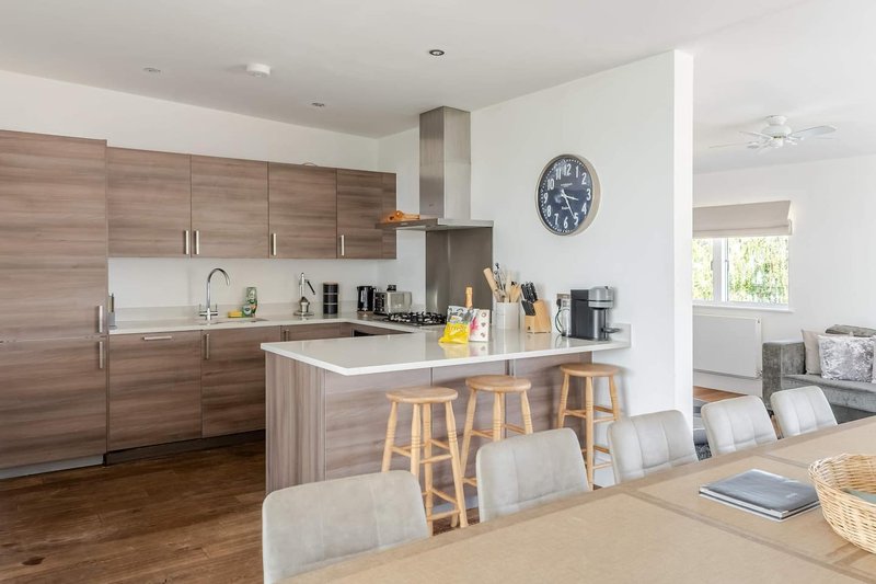 Modern kitchen with wooden cabinetry, island seating, and open-plan dining area