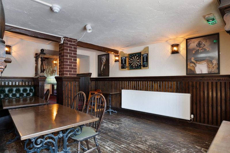 Traditional pub interior with wooden panelling, leather seating, dining table and framed wall art