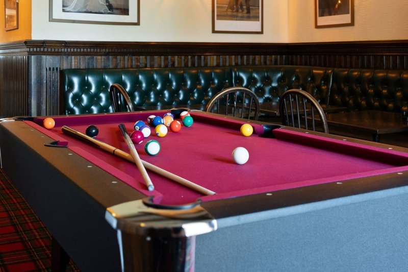 Games room with pool table, colorful balls, cues, and leather seating