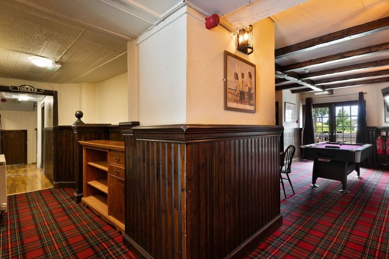 Spacious games room with wooden paneling, pool table, tartan carpet and period features