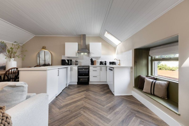 Modern kitchen with white cabinetry, herringbone wood flooring, skylight and seating area