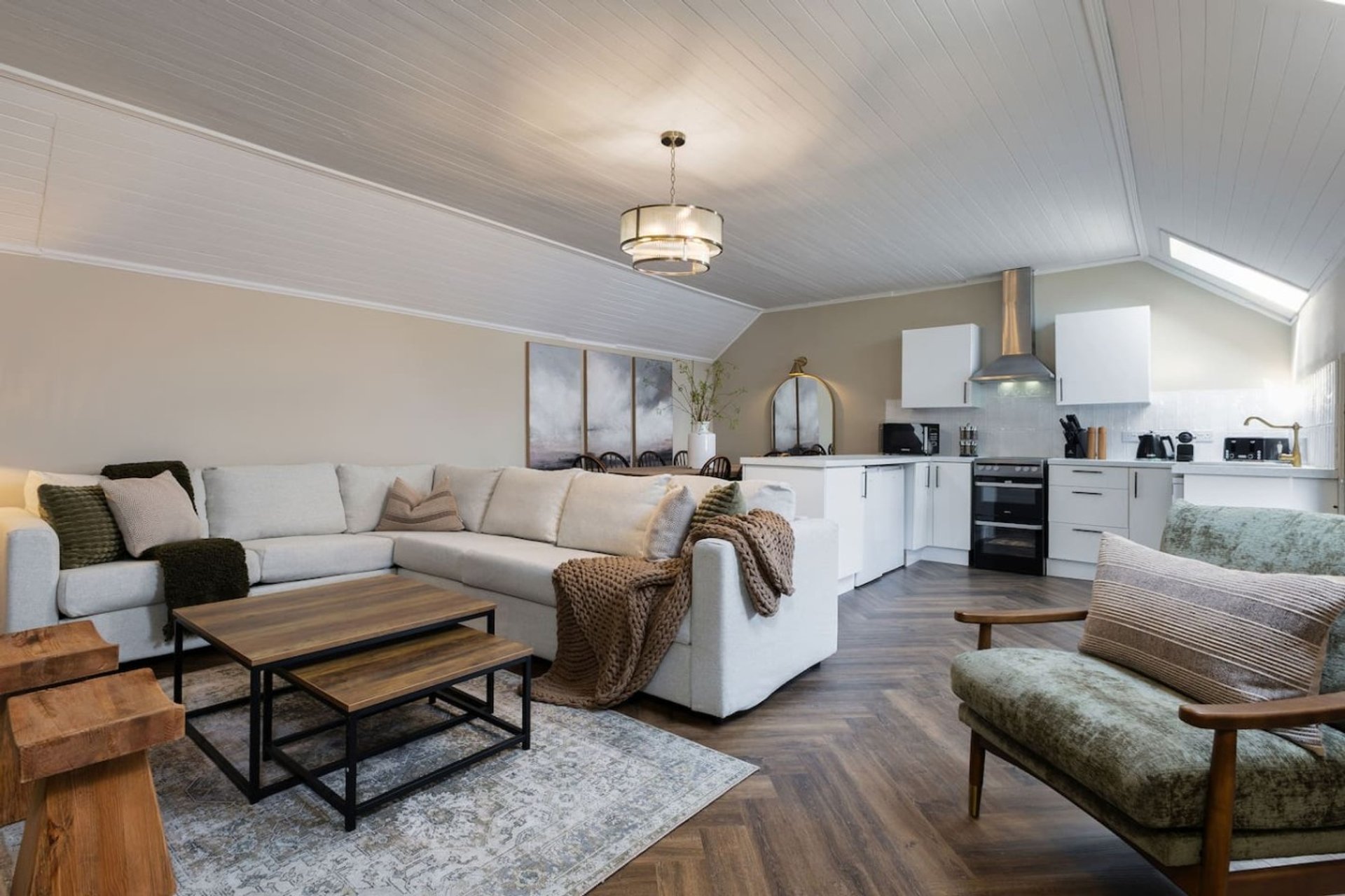 Open-plan living and kitchen area with cream sectional sofa, wooden coffee table, and modern appliances