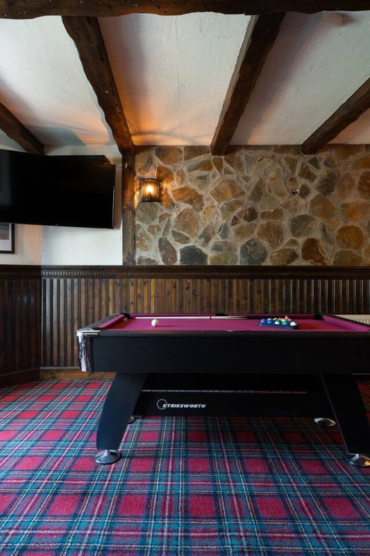 Games room with pool table, tartan carpet, stone wall and wooden beams