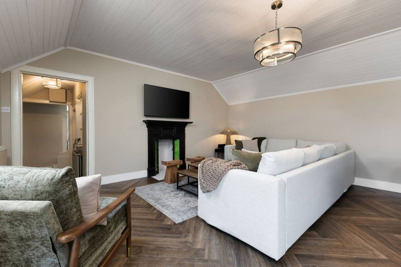 Spacious living room with white sofa, fireplace, TV, armchair and wooden flooring