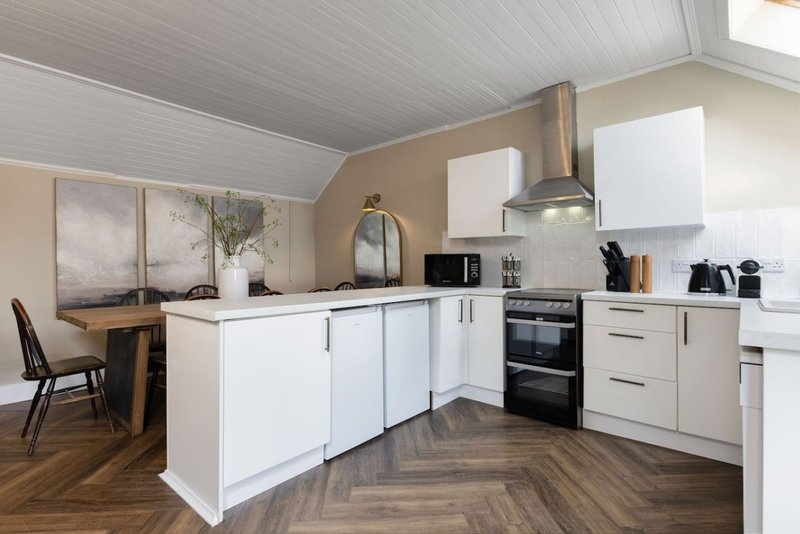 Modern kitchen with white cabinetry, island, black oven, and dining area with chair
