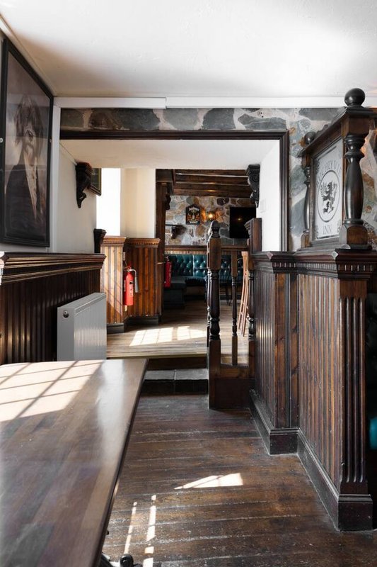 Hallway with wooden railings, dark wood flooring, white walls and doorway to further rooms