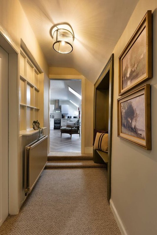 Hallway with framed artwork, ceiling light fixture, and view into living area