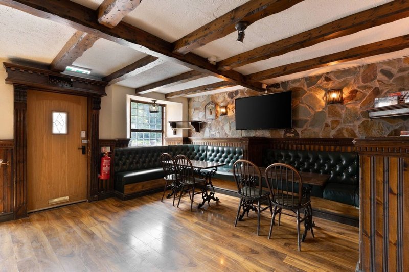 Spacious pub interior with wooden beams, fireplace, leather seating and dining area