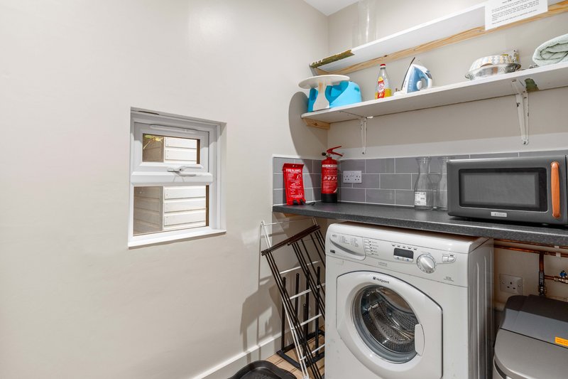 Compact laundry room with washing machine, microwave, shelving and window