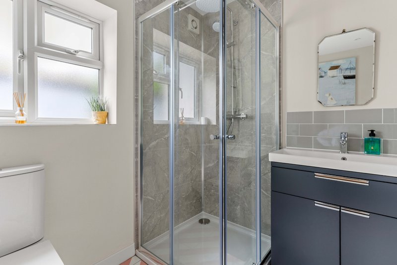 Modern bathroom with shower enclosure, dark vanity, mirror and window