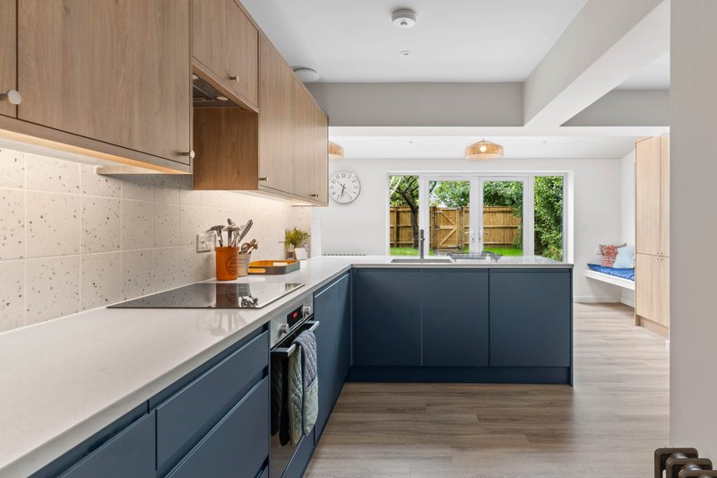 Modern kitchen with two-tone cabinetry, white countertops, and garden view windows