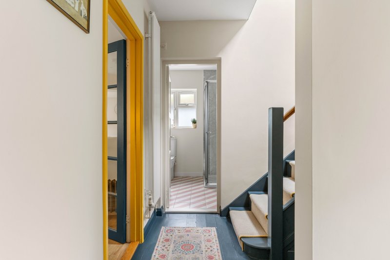 Bright hallway with yellow door, blue floor, and view through to bathroom