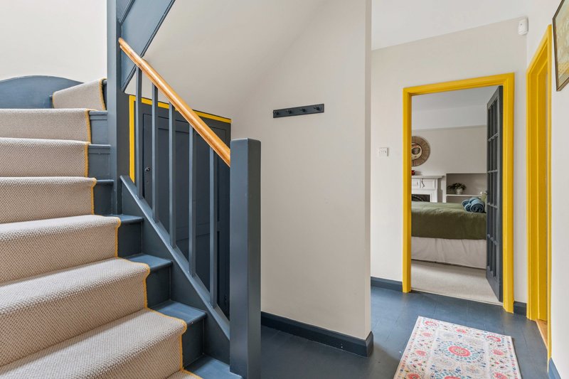 Hallway with staircase, yellow door frame, and blue flooring with rug
