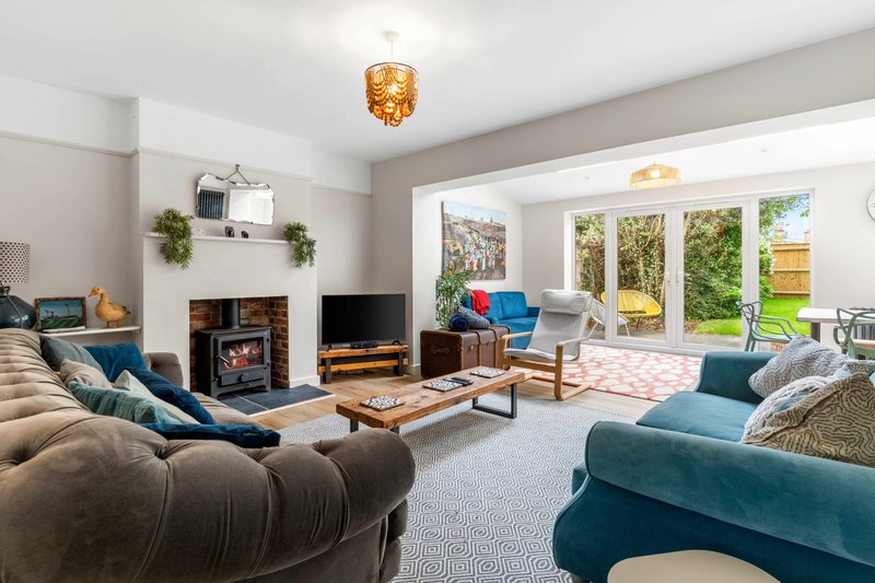 Spacious living room with fireplace, blue sofas, wooden coffee table and glass doors to garden
