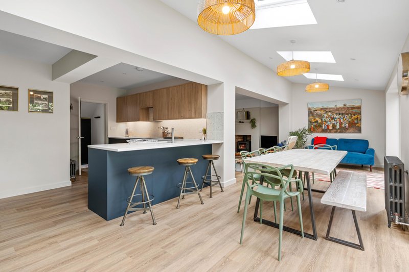 Open-plan kitchen and living area with island, dining table, blue sofa and pendant lighting