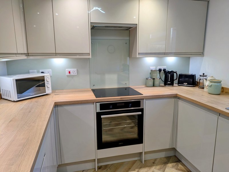 A well-equipped modern kitchen with generous worktop space, offering everything guests need for self-catering, including an oven, hob, microwave, kettle, toaster and plenty of storage.
