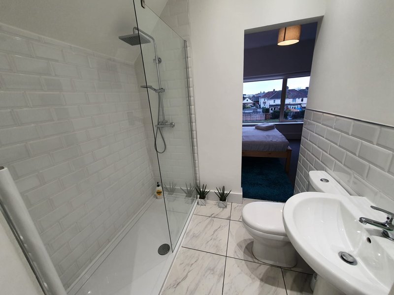 Modern bathroom with walk-in shower, white subway tiles, toilet and circular sink