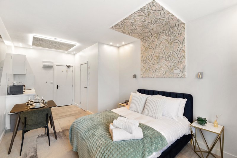Modern bedroom with double bed, desk area, and ensuite bathroom visible