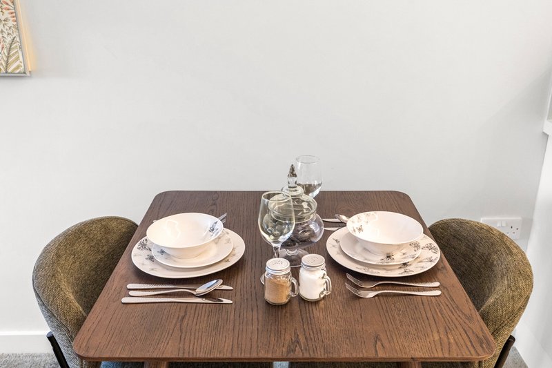 Dining table set for two with place settings, glassware, and table decor
