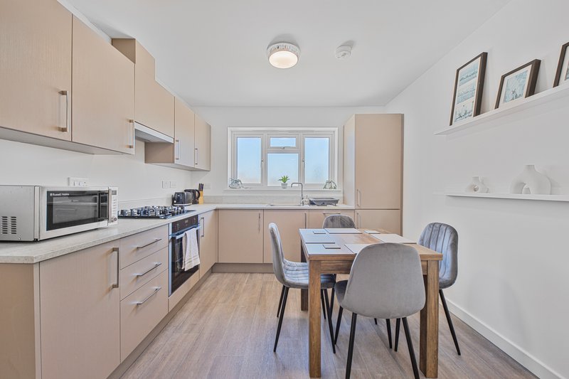 Modern kitchen and dining area with light wood cabinets, dining table and chairs, windows