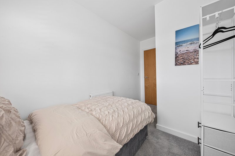 Bedroom with single bed, white wardrobe, landscape artwork, and gray carpet flooring