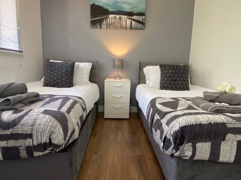 Twin bedroom with two single beds, geometric patterned bedding, and landscape artwork
