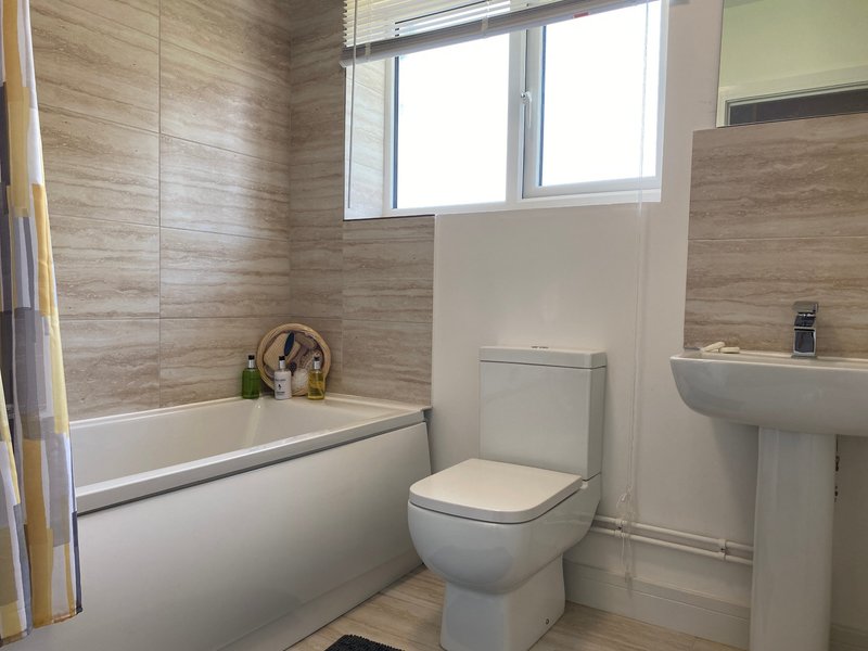 Modern bathroom with bathtub, toilet, pedestal sink and window